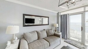 Ein modernes Wohnzimmer mit einer Couch, einem Flachbildfernseher und einem Balkon mit Blick.