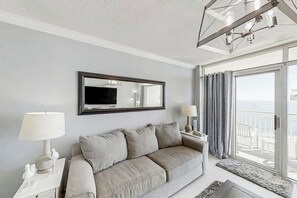 Ein modernes Wohnzimmer mit einer Couch, einem Flachbildfernseher und einem Balkon mit Blick.
