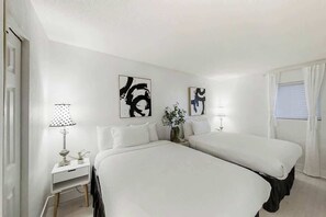 A hotel room with two beds, a nightstand, a lamp, and abstract art on the walls. - Bay Watch Resort 1408 (North Myrtle Beach)