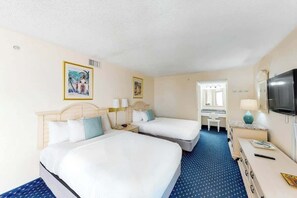 A hotel room with two beds, a desk, a television, and artwork on the walls. - Bay Watch Resort 1411 (North Myrtle Beach)