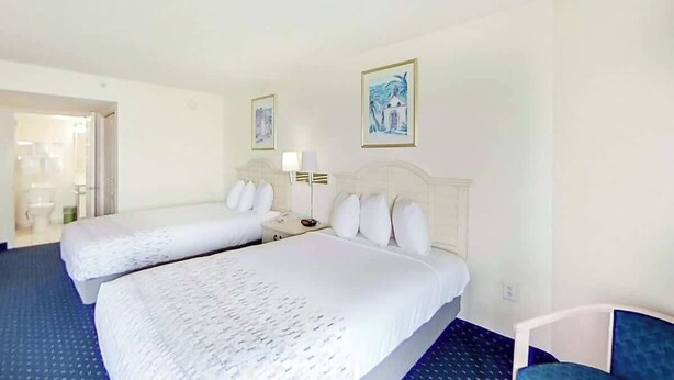 A hotel room with two beds, a nightstand, a lamp, and a chair. - Bay Watch Resort 1412 (North Myrtle Beach)