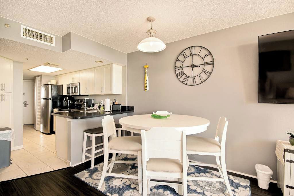 A modern kitchen with white cabinetry, a built-in island, and a round dining table with chairs.