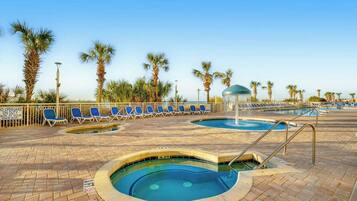 A pool area with lounge chairs and palm trees.
