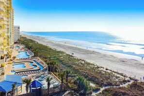 Ein Resort mit mehreren Swimmingpools, einem Strand und einem Hochhaus.