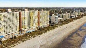Ein Strandhotel mit mehreren Hochhäusern, einem Sandstrand und einem klaren Himmel.