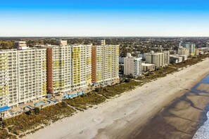 Ein Strandhotel mit mehreren Hochhäusern, einem Sandstrand und einem klaren Himmel.
