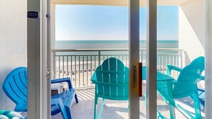 Ein Balkon mit Blick auf den Strand, ein Stuhl und ein Tisch.