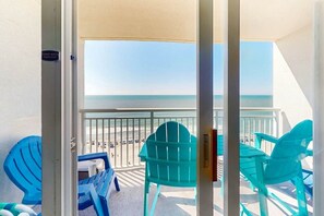 Ein Balkon mit Blick auf den Strand, ein Stuhl und ein Tisch.