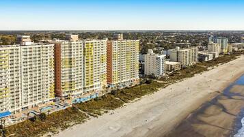 A coastal residential area with high-rise buildings, a beach, and a clear sky.