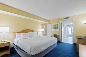 A hotel room with a bed, a desk, a chair, and a door leading to another room. - Bay Watch Resort 1603 (North Myrtle Beach)