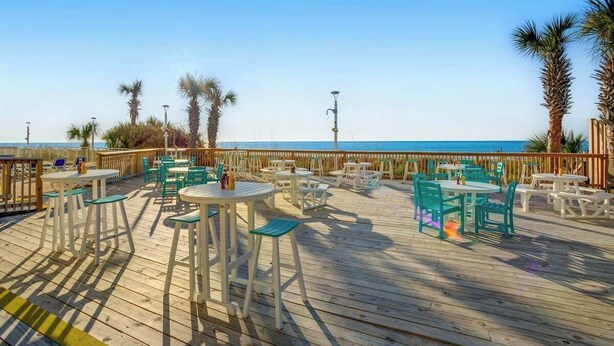 An outdoor deck with tables and chairs, overlooking a body of water. - Bay Watch Resort 1603 (North Myrtle Beach)