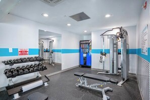 Een sportschool met trainingsapparatuur, gewichten en een bank.