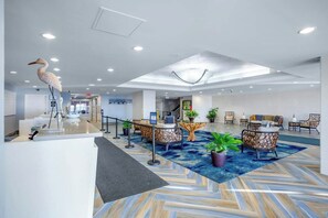 A hotel lobby with a reception desk, seating area, and a large bird sculpture. - Bay Watch Resort 1605 (North Myrtle Beach)