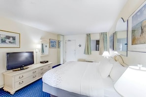 Ein Hotelzimmer mit Bett, Fernseher, Schminktisch und Spiegel.