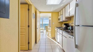 Eine Küche mit Blick ins Freie, eine Tür zu einem Balkon und ein Kühlschrank.