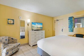 A hotel room with a bed, a dresser, a chair, a television, and a painting on the wall. - Bay Watch Resort 1503 (North Myrtle Beach)