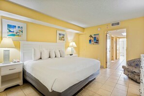 Ein Hotelzimmer mit einem Bett, zwei Nachttischen, einem Sessel und Bildern an den Wänden.