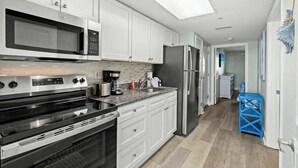 A modern kitchen with white cabinets, stainless steel appliances, and a skylight. - Bay Watch Resort 1506 (North Myrtle Beach)