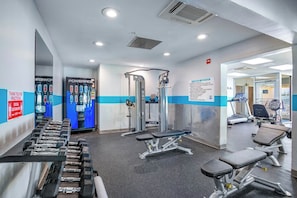 Uma academia com equipamentos de exercício, esteiras e um espelho grande na parede.