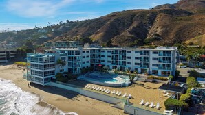 A beachfront hotel with multiple floors, a pool, and beachside amenities. - Carbon & Coast by Avantstay Beachfront 2BR + Shared Pool & Spa On the Sand (Malibu)