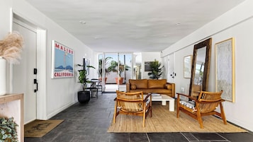A modern living room with a sofa, two wicker chairs, a coffee table, and a large mirror.