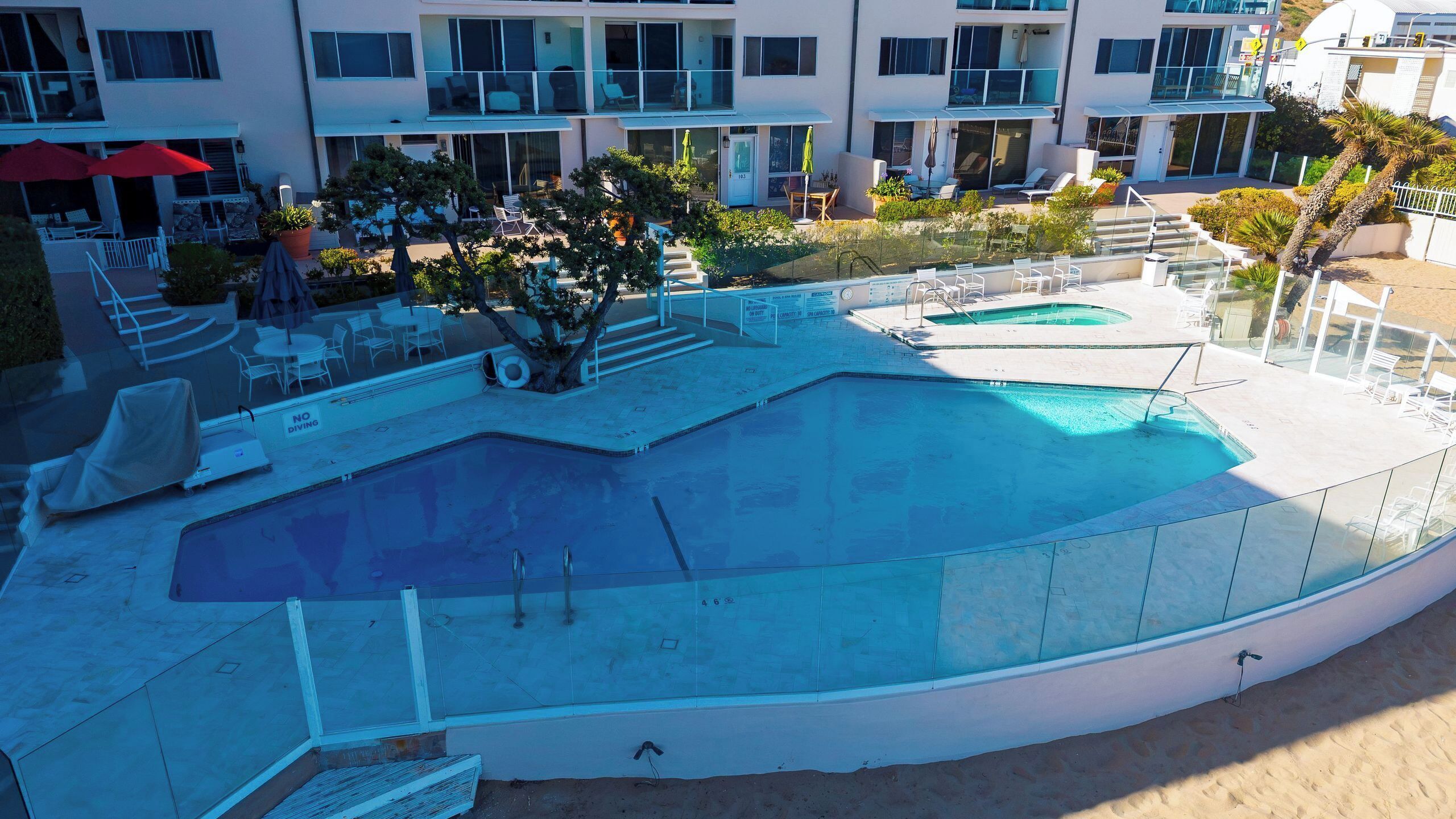 Piscina no terraço com espreguiçadeiras e escadaria de acesso ao edifício.