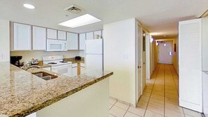 A kitchen with white cabinets, a granite countertop, and a microwave. - Bay Watch Resort 1512 (North Myrtle Beach)