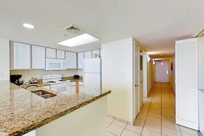 A kitchen with white cabinets, a granite countertop, and a microwave. - Bay Watch Resort 1512 (North Myrtle Beach)