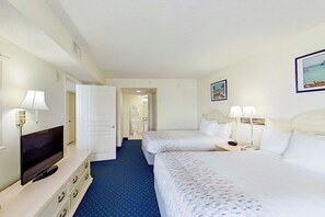 Een hotelkamer met twee bedden, een televisie, een bureau met een lamp en een schilderij aan de muur.