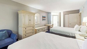 Ett hotellrum med två sängar, en byrå, ett skrivbord och en stol.