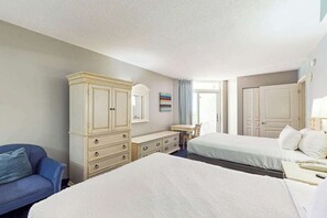 Ein Hotelzimmer mit zwei Betten, einem Schminktisch, einem Schreibtisch und einem Stuhl.