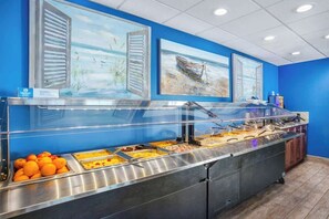 A buffet area with a blue wall and artwork depicting boats and water. - Bay Watch Resort 1531 (North Myrtle Beach)