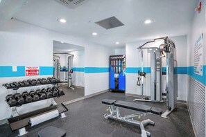 A gym with weightlifting equipment, benches, and a mirrored wall. - Bay Watch Resort 1531 (North Myrtle Beach)