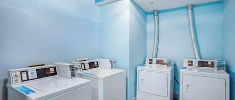 Una sala de bugaderia amb quatre rentadores i dues assecadores, equipada amb panells de control i mànegues.