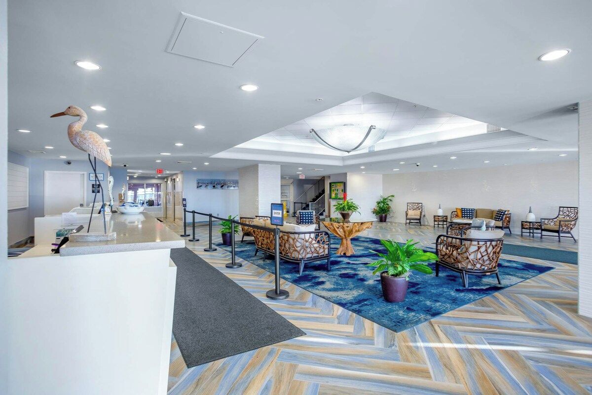 A hotel lobby with a reception desk, seating area, and a large decorative bird sculpture.