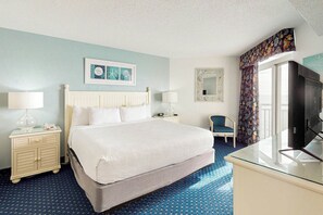 Una camera d'albergo con un letto, comodini, una sedia, televisione, una finestra con tende e opere d'arte appese al muro.