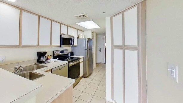 A modern kitchen with stainless steel appliances, a microwave, and a coffee maker. - Bay Watch Resort 1613 (North Myrtle Beach)