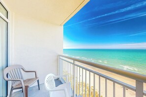 A balcony with two chairs, a view of the ocean, and a clear sky. - Bay Watch Resort 1614 (North Myrtle Beach)