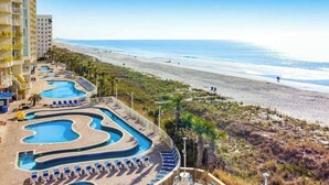 Ein Resort mit mehreren Swimmingpools, einem Strand und einem Hochhaus.