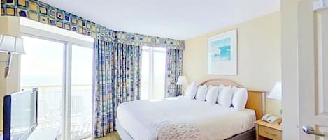 Une chambre d’hôtel avec un lit, une télévision, un bureau et une fenêtre avec des rideaux.