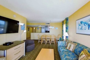 A compact living space with a sofa, a dining table with chairs, a television, and a kitchenette area. - Bay Watch Resort 1702 (North Myrtle Beach)