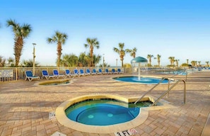 A pool area with lounge chairs, palm trees, and a lifeguard on duty. - Bay Watch Resort 1702 (North Myrtle Beach)
