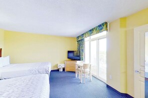 A hotel room with two beds, a desk with a chair, a television, and a window with curtains. - Bay Watch Resort 1701 (North Myrtle Beach)