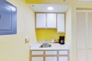 A small kitchenette with a sink, cabinets, and a coffee maker. - Bay Watch Resort 1701 (North Myrtle Beach)