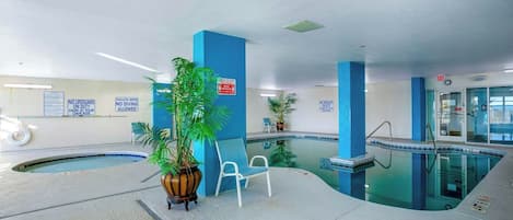 An indoor swimming pool with blue walls, a chair, and a potted plant.