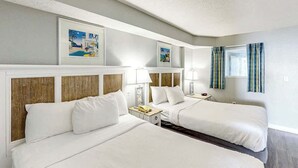 A hotel room with two beds, a nightstand, a lamp, and framed pictures on the wall. - Bay Watch Resort 1704 (North Myrtle Beach)