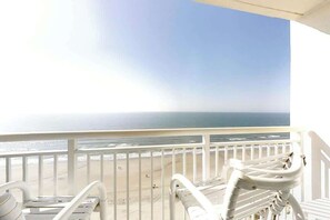 Un balcon avec des balustrades blanches donnant sur une plage.
