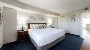A hotel room with a large bed, two bedside tables with lamps, a wall clock, and decorative wall art. - Bay Watch Resort 1719 (North Myrtle Beach)