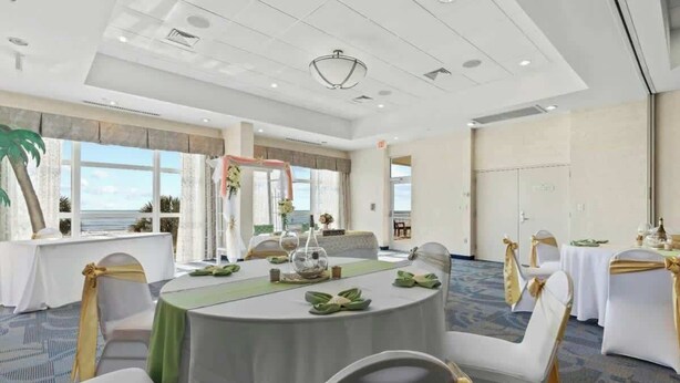 A conference room with round tables, white chairs, and a view of the outdoors. - Bay Watch Resort 1719 (North Myrtle Beach)