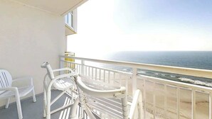 A balcony with white chairs and a railing overlooking a beach. - Bay Watch Resort 1719 (North Myrtle Beach)